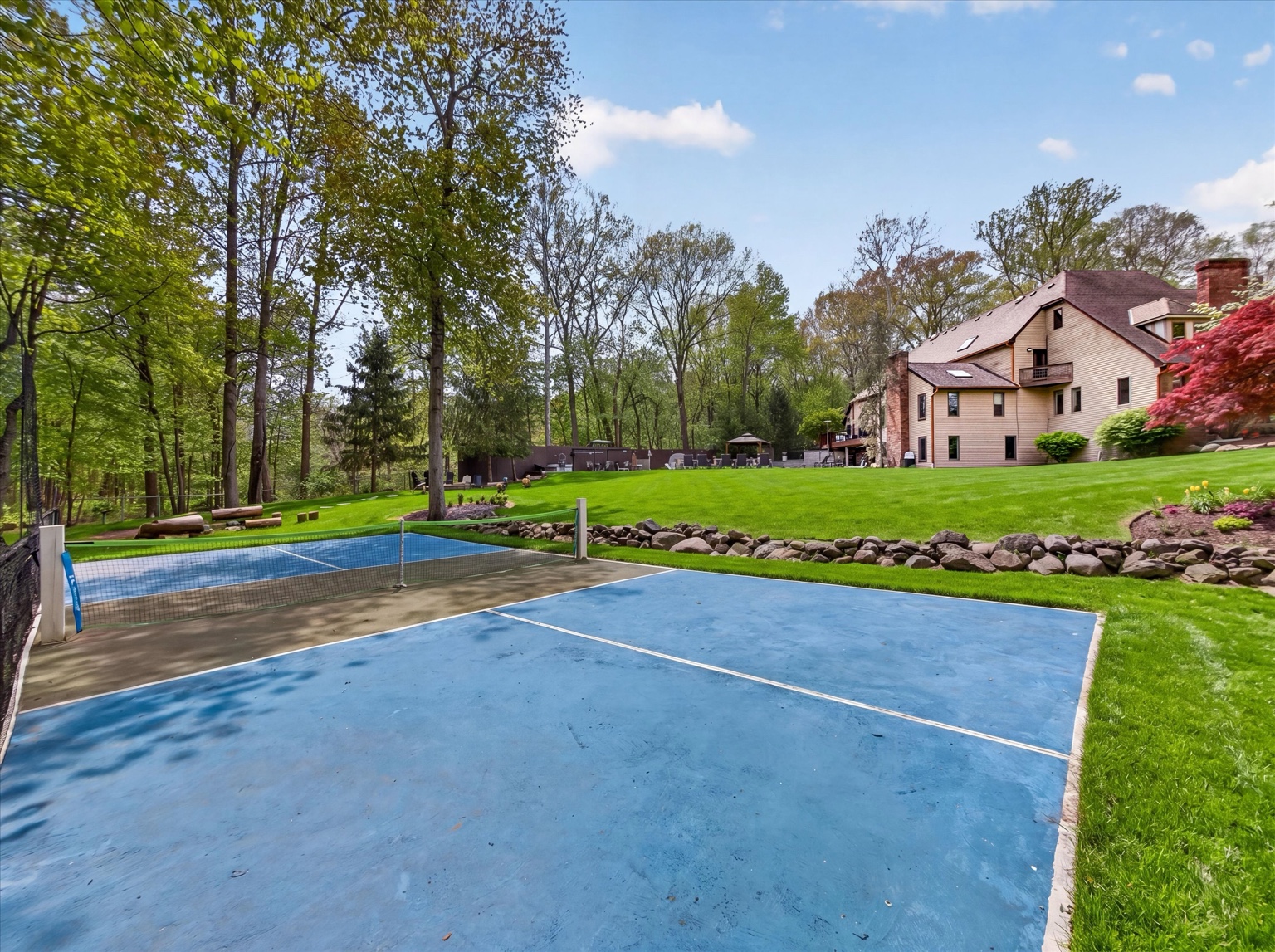 Blue pickleball court with the home and lawn beyond
